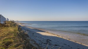 Une plage avec un rivage sablonneux et un ciel bleu dégagé.