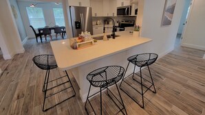 Una cocina moderna con una isla central, taburetes de bar e iluminación colgante.