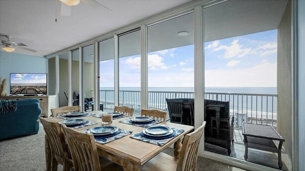 A dining area with a view of the ocean, a ceiling fan, and a television on the left. - Welcome to our Beach Dream View, The Sunrise and Sunset are breath taking (Gulf Shores)