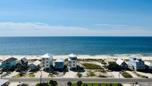 A coastal residential area with houses along the beachfront, a clear sky, and a road in the foreground. - Welcome to our Beach Dream View, The Sunrise and Sunset are breath taking (Gulf Shores)