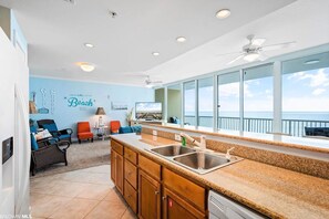 A kitchen with a large window, a ceiling fan, and a view of the ocean.