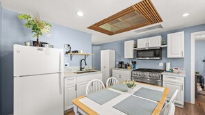 Una cucina moderna con mobili bianchi, un forno a microonde integrato e un'area pranzo con tavolo e sedie in legno.
