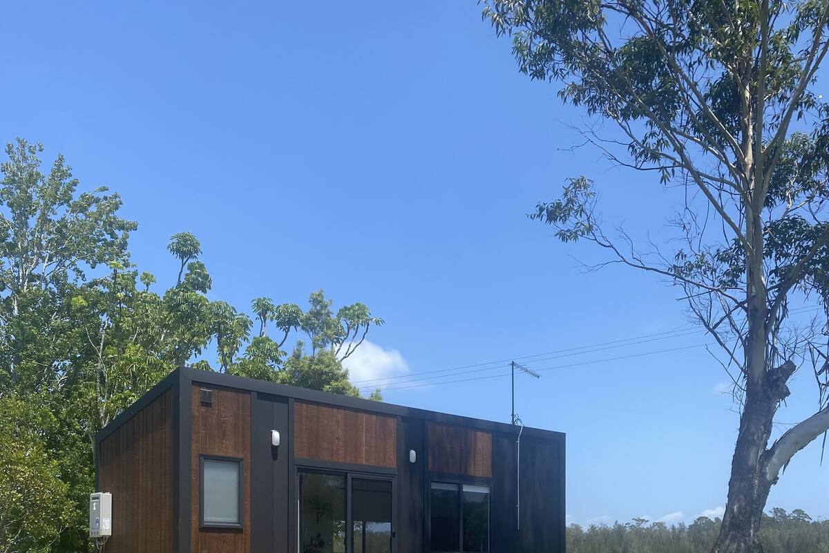 Ein modernes Gebäude mit Holzfassade, großen Fenstern und einer Terrassenfläche.