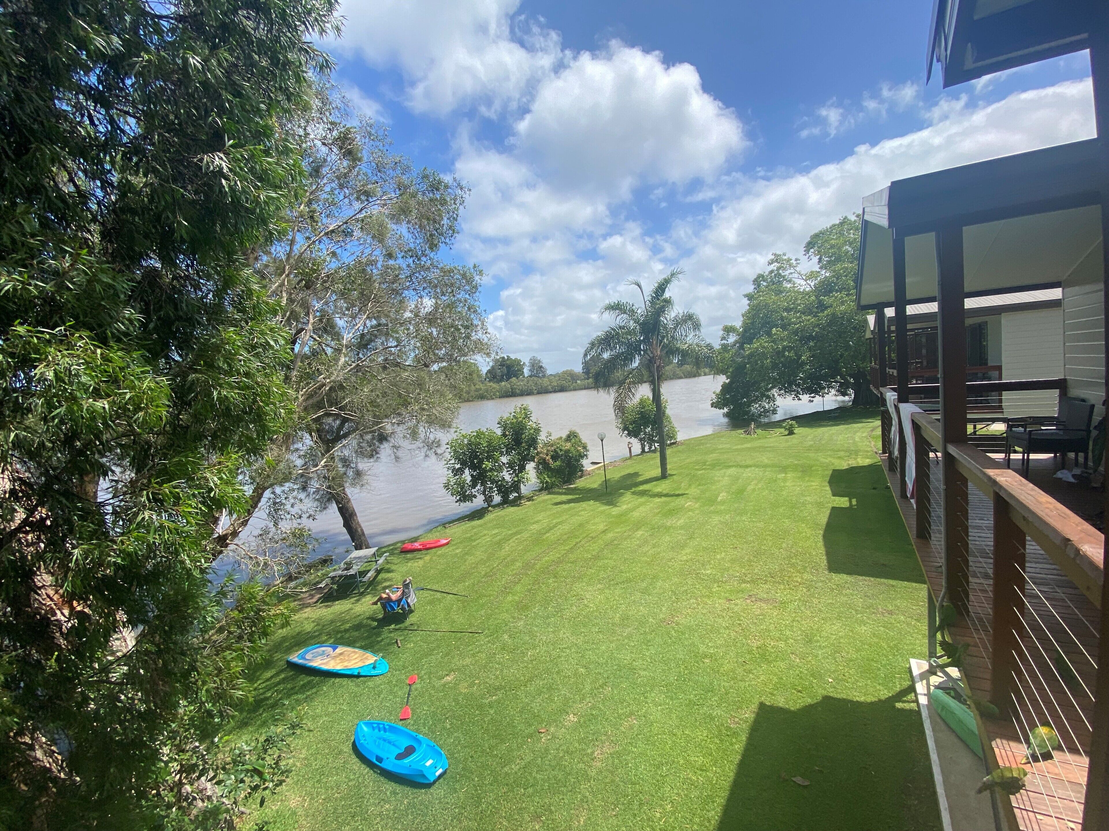 Um quintal com gramado, dois caiaques, um remo e um pequeno lago.