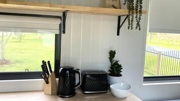A kitchen with a wooden countertop, a coffee maker, a toaster, and a small potted plant.