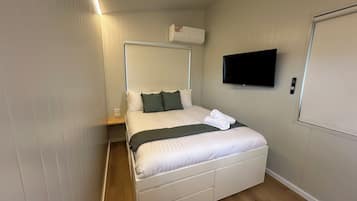 Una habitación de hotel con cama, televisión, aire acondicionado y puerta.