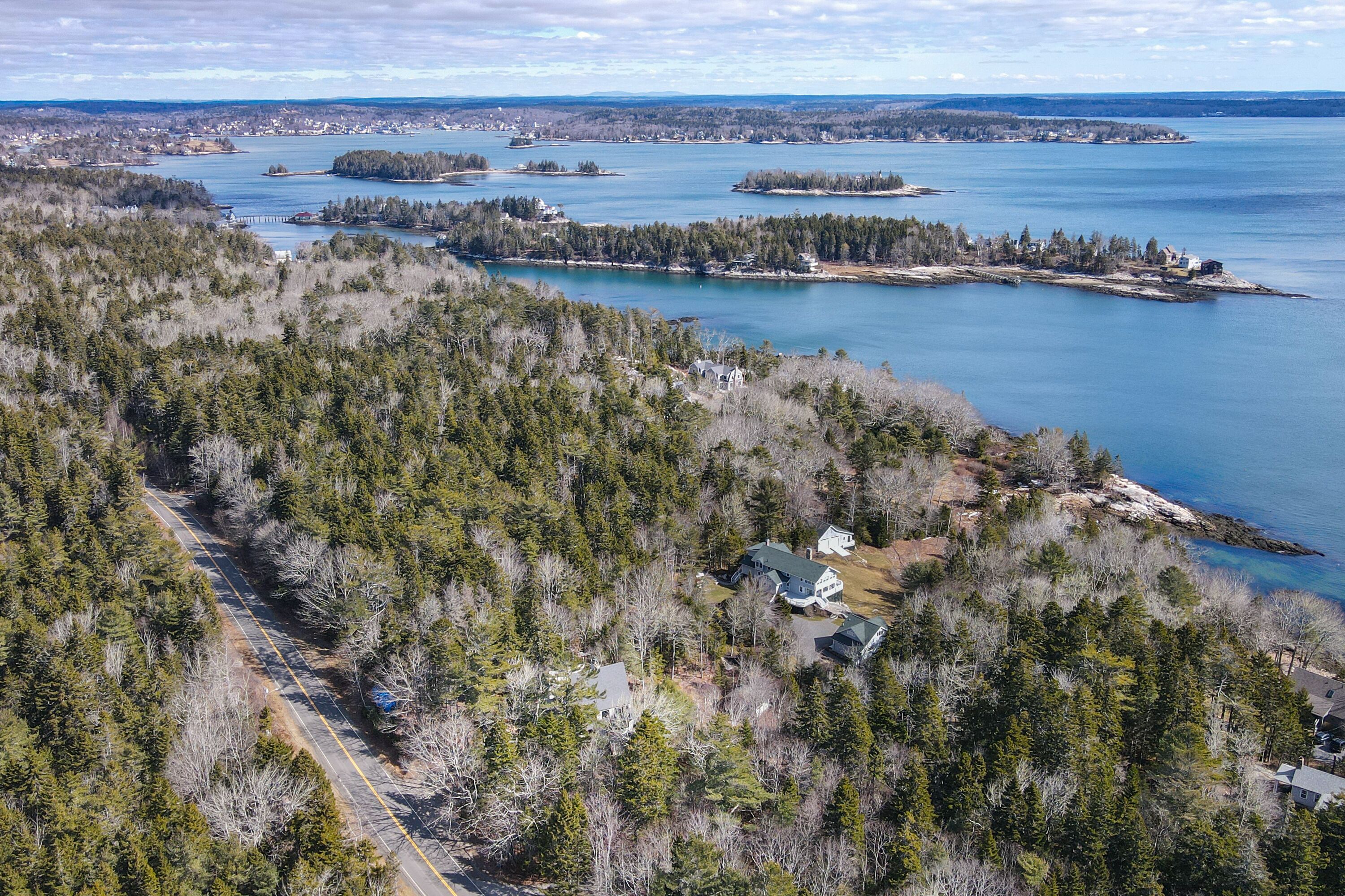 An aerial view of a forested area with a road and a large house surrounded by trees.