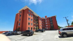 Un edificio rosso a più piani con un parcheggio davanti.