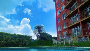 Una piscina con un cielo azzurro limpido e un edificio rosso sullo sfondo.
