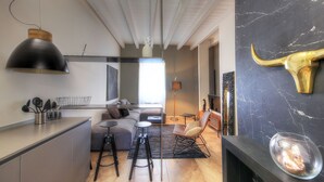 A modern kitchen with a large black pendant light, a wooden bowl on the counter, and a kitchen island with stools. - Luxury Living in the Heart of the City (Cagliari)