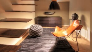 A modern interior with a staircase, a leather chair, a geometric pouf, and a desk with a lamp. - Luxury Living in the Heart of the City (Cagliari)