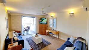 Ein Wohnzimmer mit Sofa, Couchtisch, Fernseher und Schreibtisch.