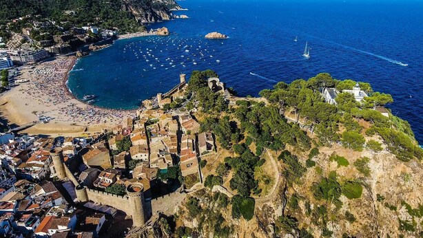 An aerial view of a coastal town with a historic fortification, a beach, and a marina. - Josep Folch – Center, Parking & A/C Tossa (Tossa De Mar)