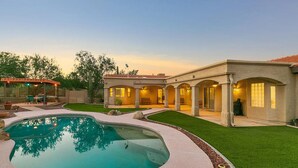 A pool with a patio area, a covered seating area, and a building with arched walkways. - Mountain Home Pool VIEWS Garage FUN Backyard Spacious Private Close to UofA
 (Tucson)