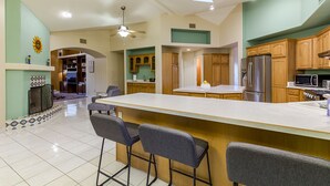 A spacious kitchen with a large island, wooden cabinets, and a built-in microwave. - Mountain Home Pool VIEWS Garage FUN Backyard Spacious Private Close to UofA
 (Tucson)