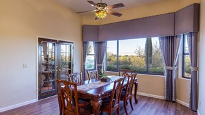 A dining room with a large table, six chairs, and a ceiling fan. - Mountain Home Pool VIEWS Garage FUN Backyard Spacious Private Close to UofA
 (Tucson)