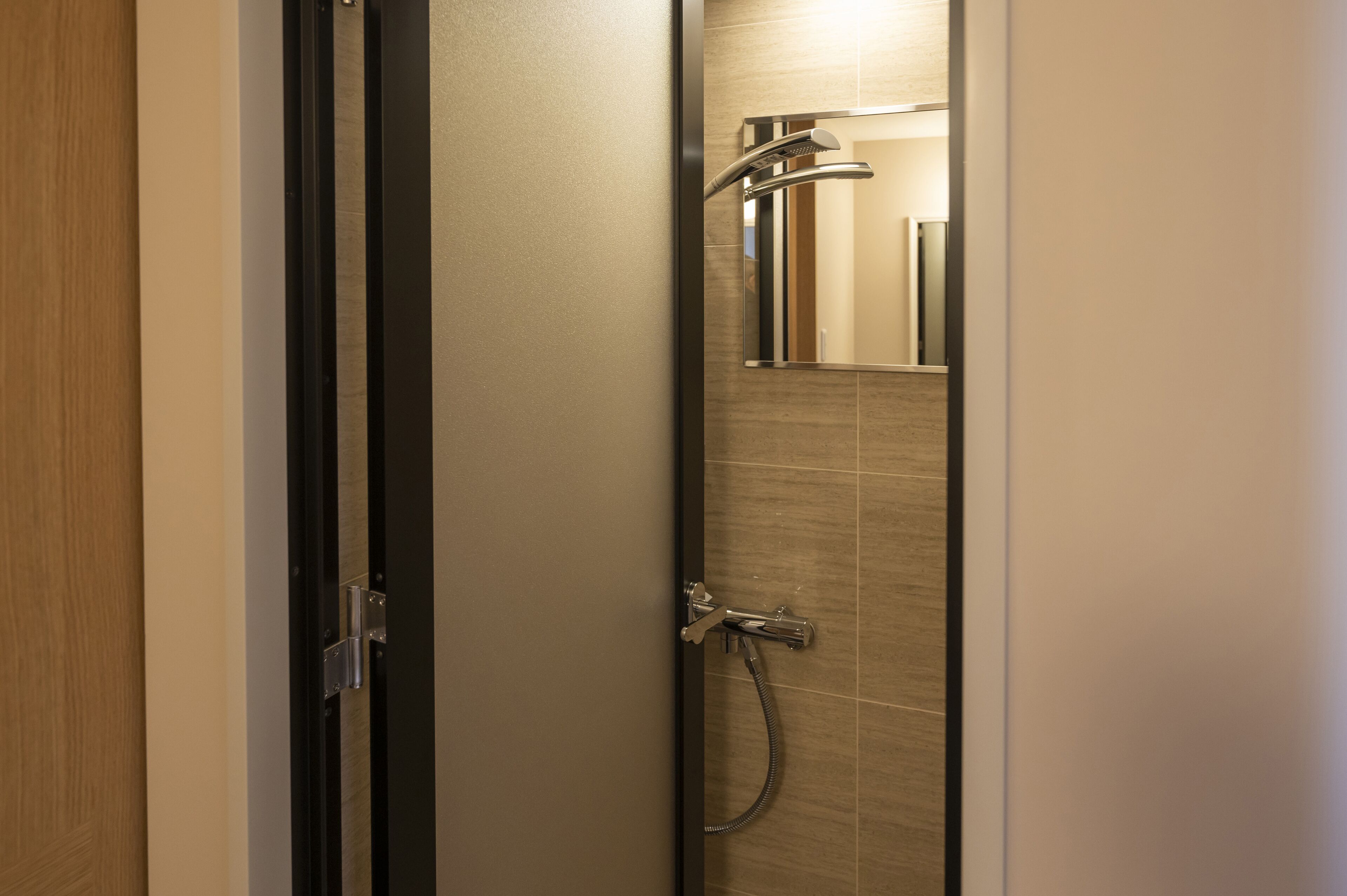 Un baño moderno con ducha, espejo y puerta.