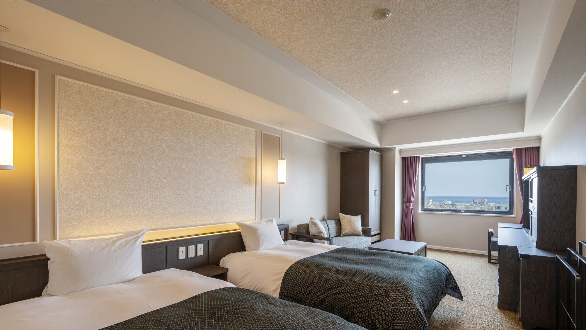 A hotel room with two beds, a desk, a chair, a large window with a view, and a wall-mounted TV.