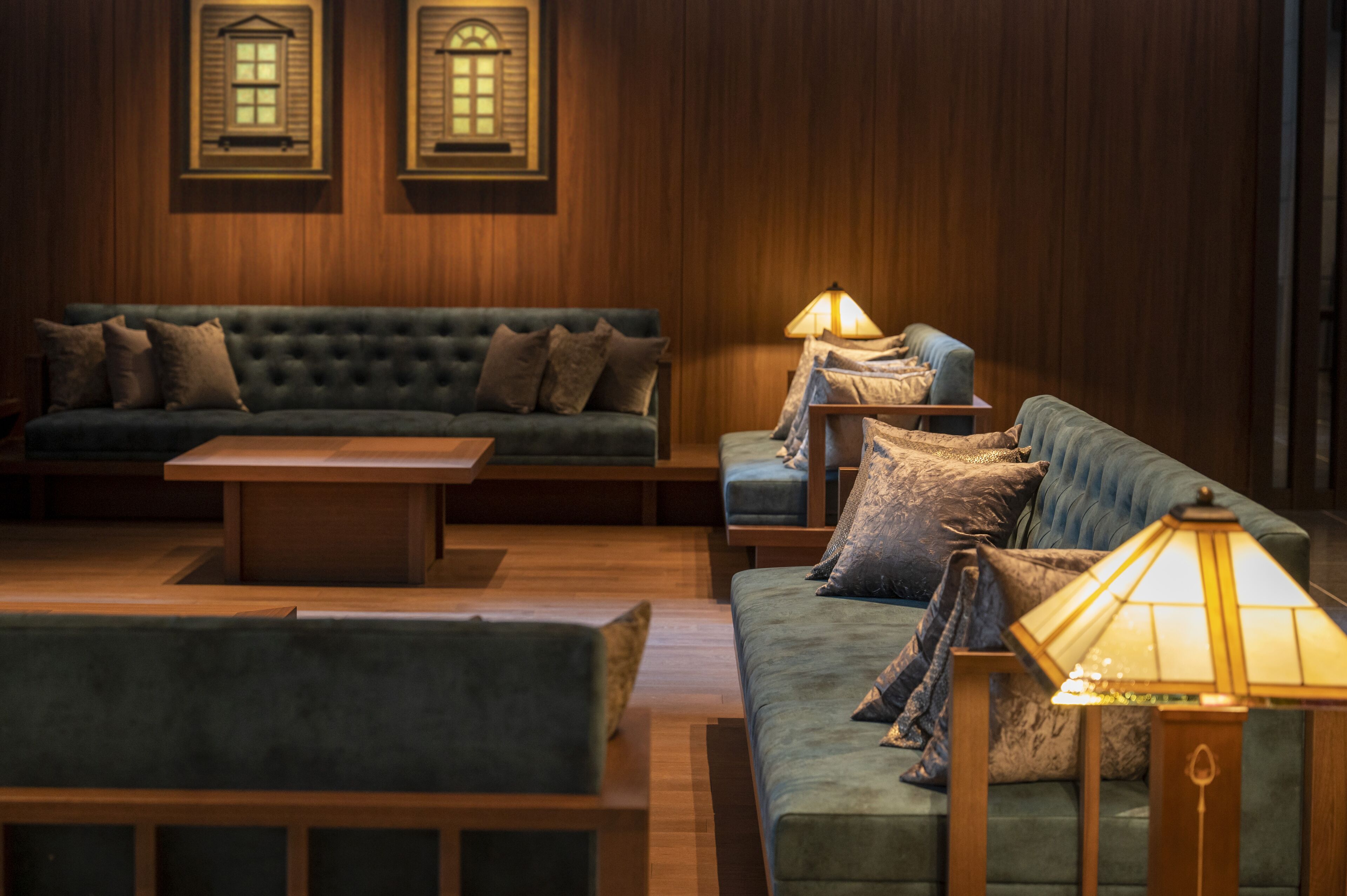 A cozy room with a dark green sofa, a wooden coffee table, and a lamp.