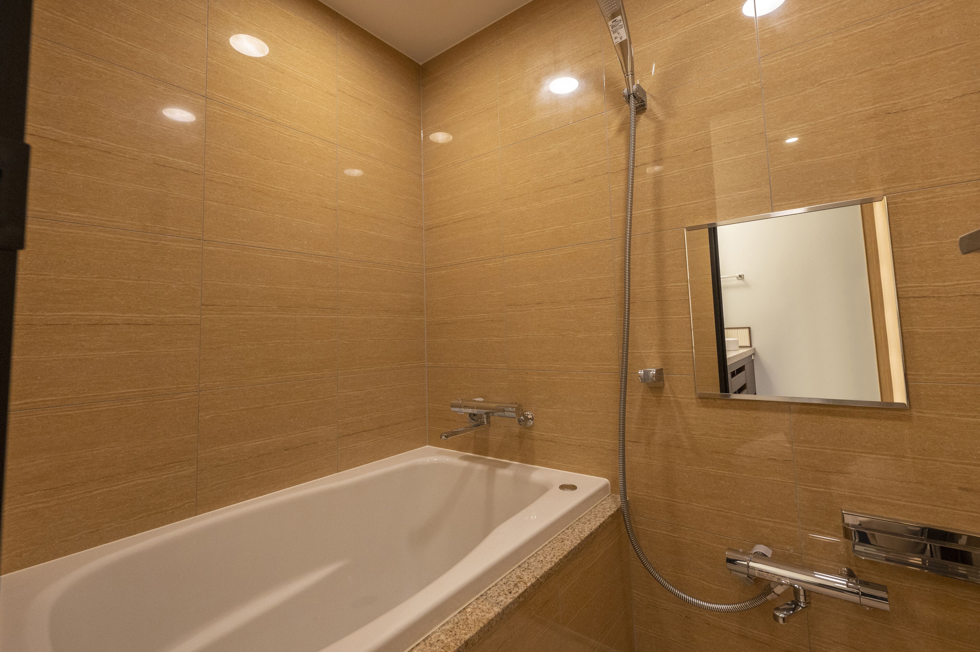 A modern bathroom with a large bathtub, a shower, and a mirror.