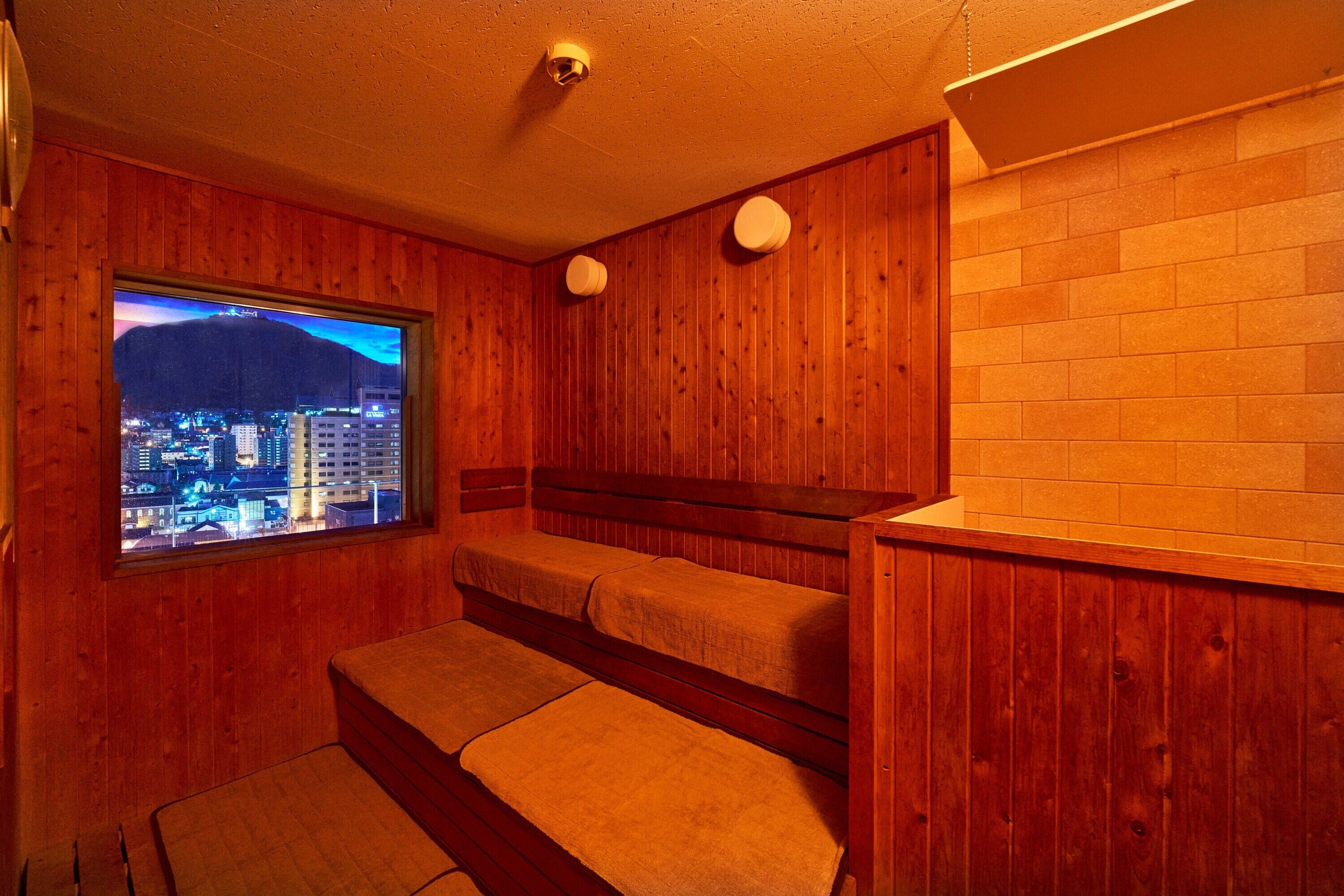 A wooden room with a window overlooking a cityscape at night.