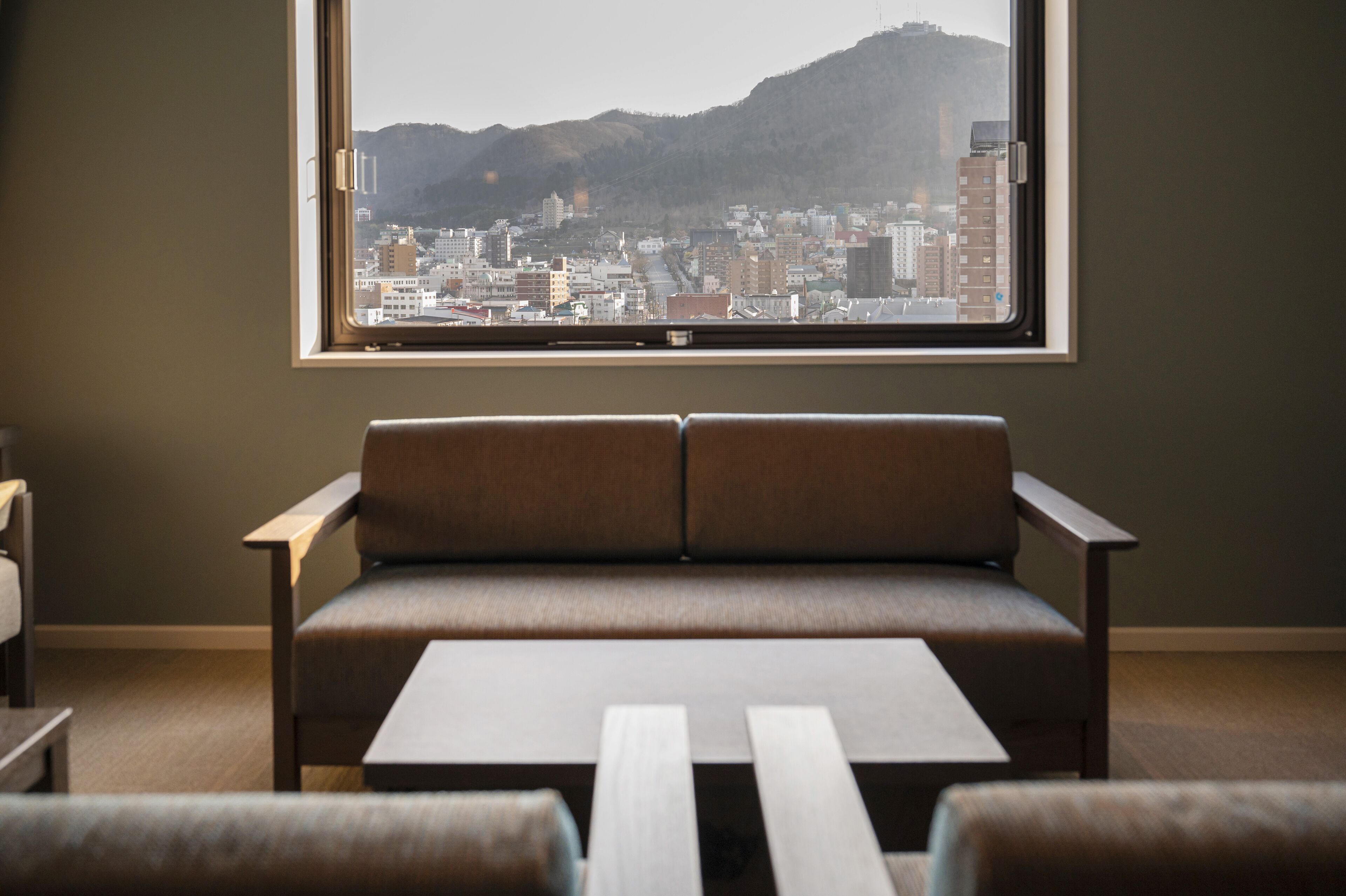 A room with a large window, a sofa, and a small table.