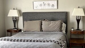 Una camera da letto con un letto grande, due comodini, un tavolino e un poggiapiedi.