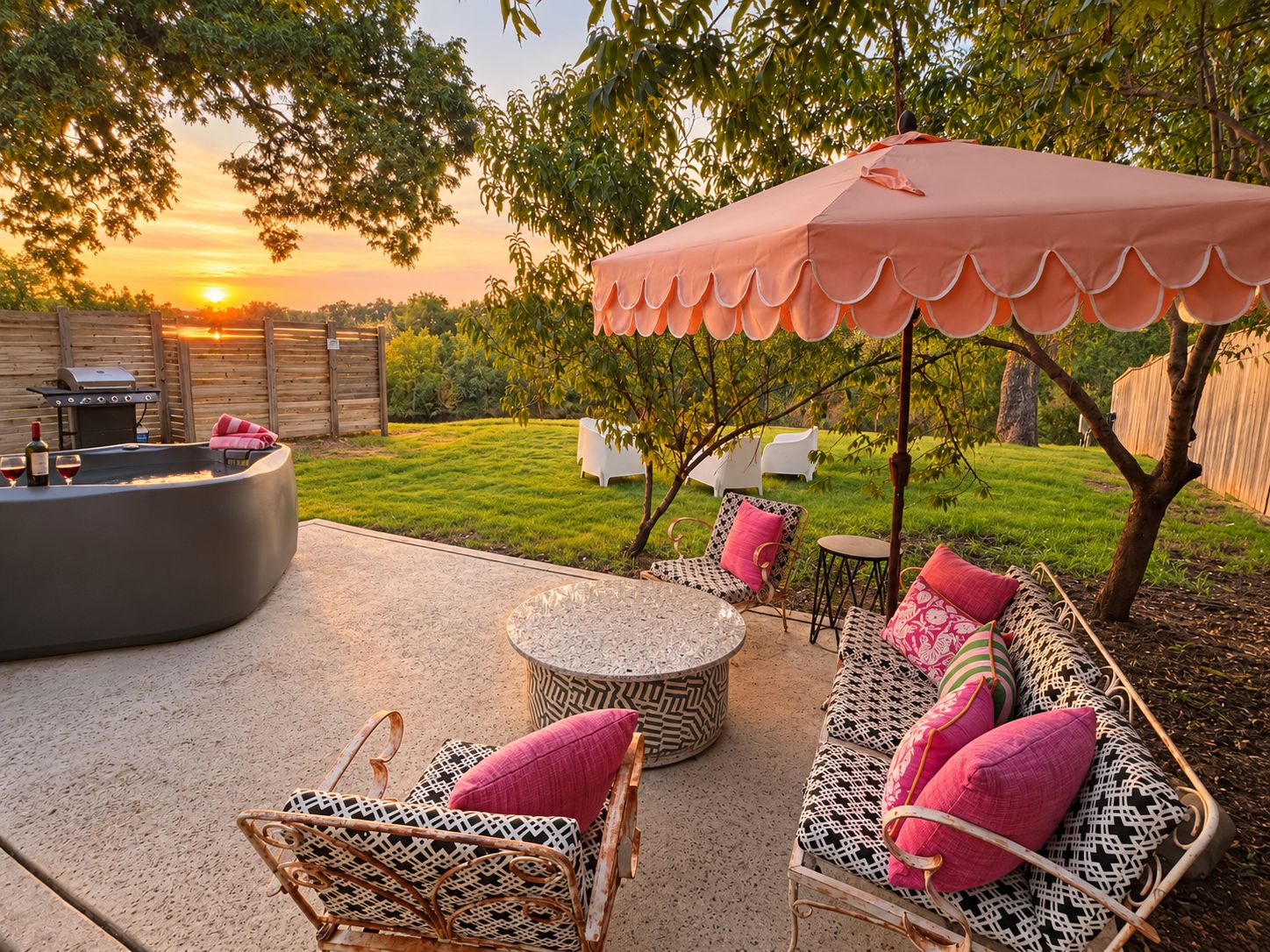 Une terrasse extérieure avec une table ronde, des chaises en osier et un espace salon abrité.