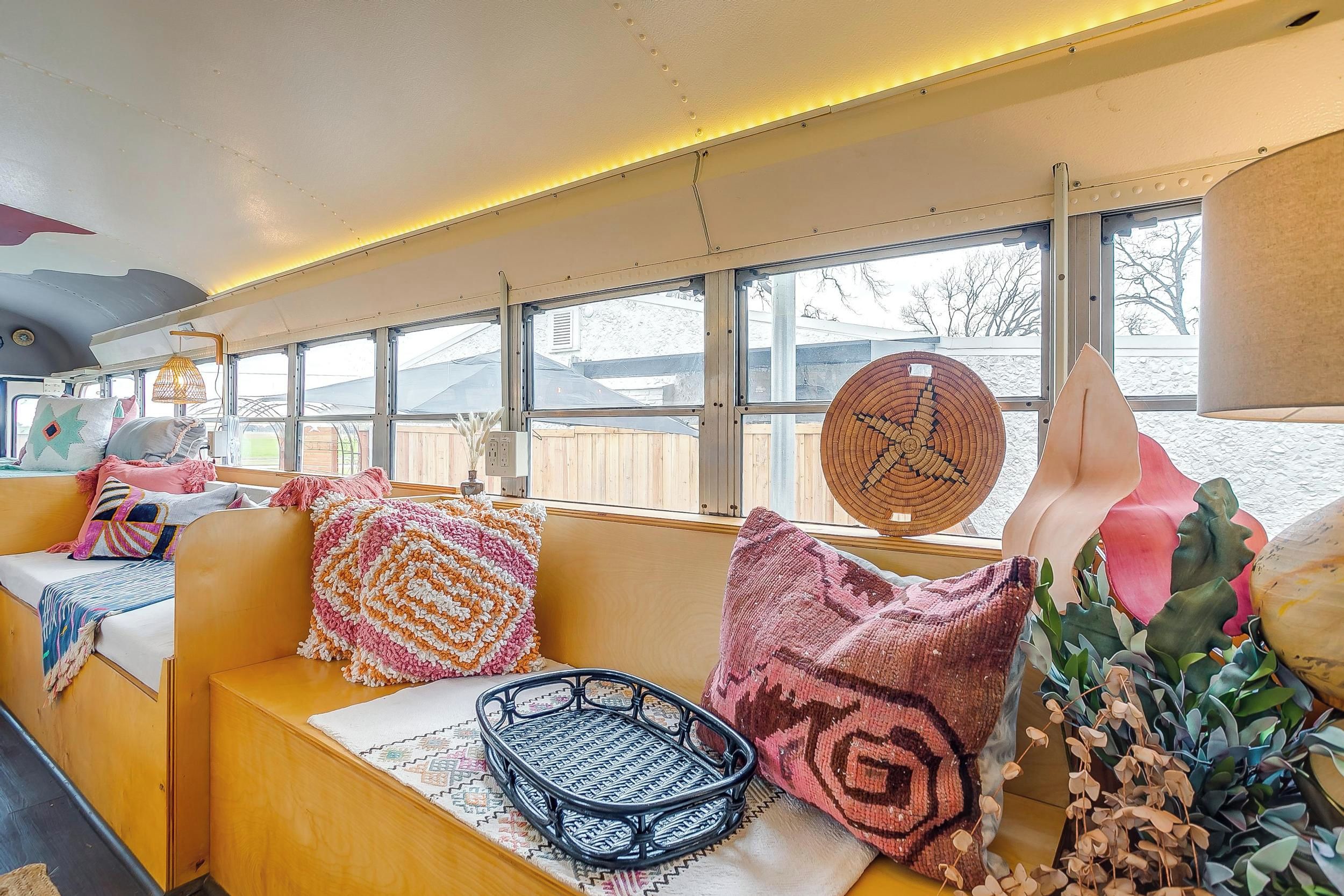 A bus interior with seating, large windows, and a ceiling with lights.