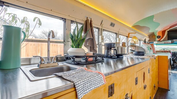 A kitchen with a stainless steel sink, a potted plant, and a coffee maker. - Romantic lakefront skoolie for 4: queen, twins, hot tub and private bathhouse (Granbury)