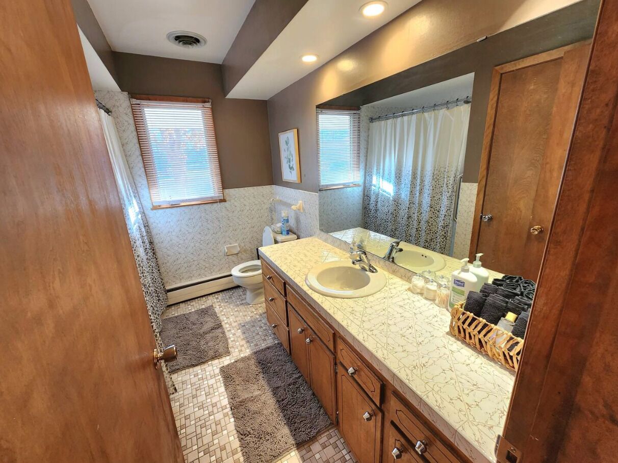 A bathroom with a sink, mirror, and wooden cabinets.