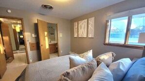 A bedroom with a bed, pillows, a window, and artwork on the wall.