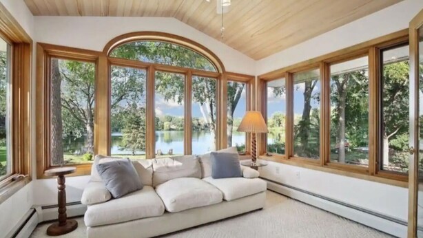 A room with a large arched window, a white sofa, and a lamp.