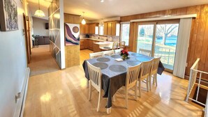 A spacious dining area with a round table, wooden flooring, and a view of the outdoors.