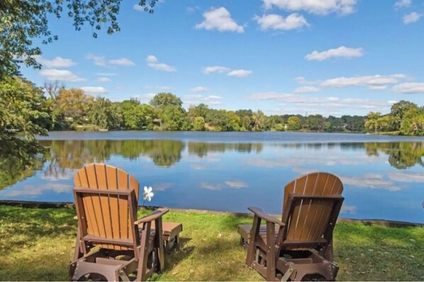 Two wooden Adirondack chairs facing a calm lake with a clear sky. - Lake Retreat, Year Round Hot Tub, Pool Table, Kayaks (Fridley)