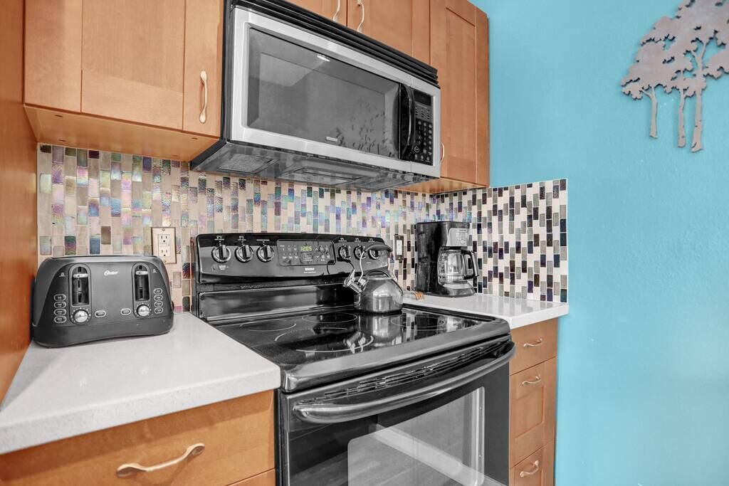 A kitchen with wooden cabinets, a microwave, a stove, a toaster, and a coffee maker.