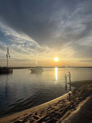 Atardecer sobre un cuerpo de agua tranquila con un bote y dos personas pescando.