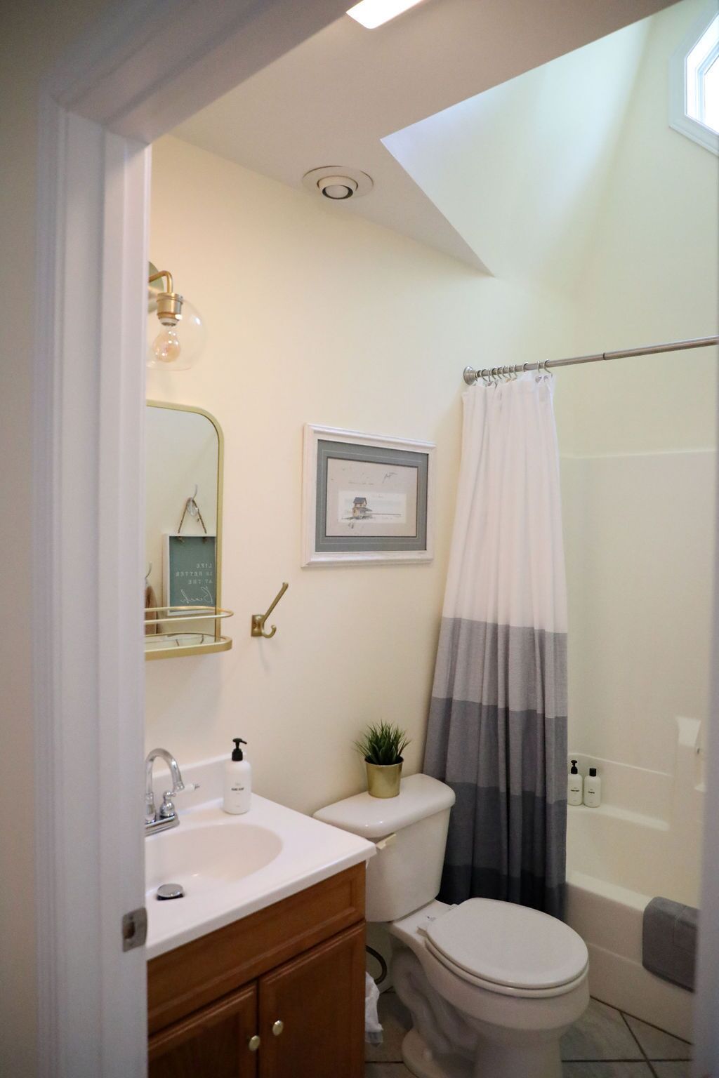 A bathroom with a white sink, a toilet, a shower curtain, and a framed picture on the wall.