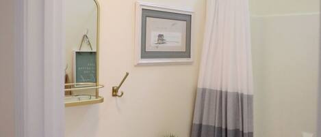 A bathroom with a white sink, a toilet, a shower curtain, and a framed picture on the wall.