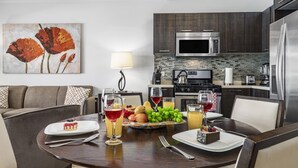A modern kitchen with dark wood cabinets, stainless steel appliances, and a dining area with a round table set for a meal. - Beautiful One Bedroom Ground Level @ PalmAruba (Noord)