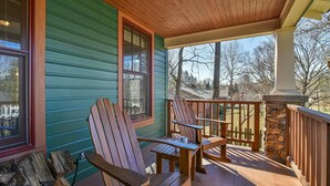 A wooden deck with Adirondack chairs and a stone pillar.