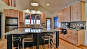 A spacious kitchen with a large island, wooden cabinets, and a modern stove.