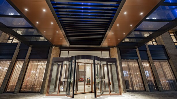 A hotel entrance with a revolving door, glass panels, and a modern ceiling design. - Qing Dao bu ke bu zhu hotel (Qingdao)