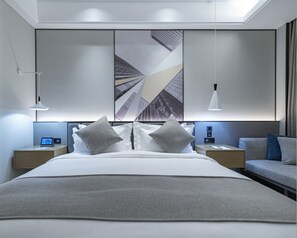 Ein modernes Hotelzimmer mit einem großen Bett, Nachttischen, einem Schreibtisch und einem großen Fenster.