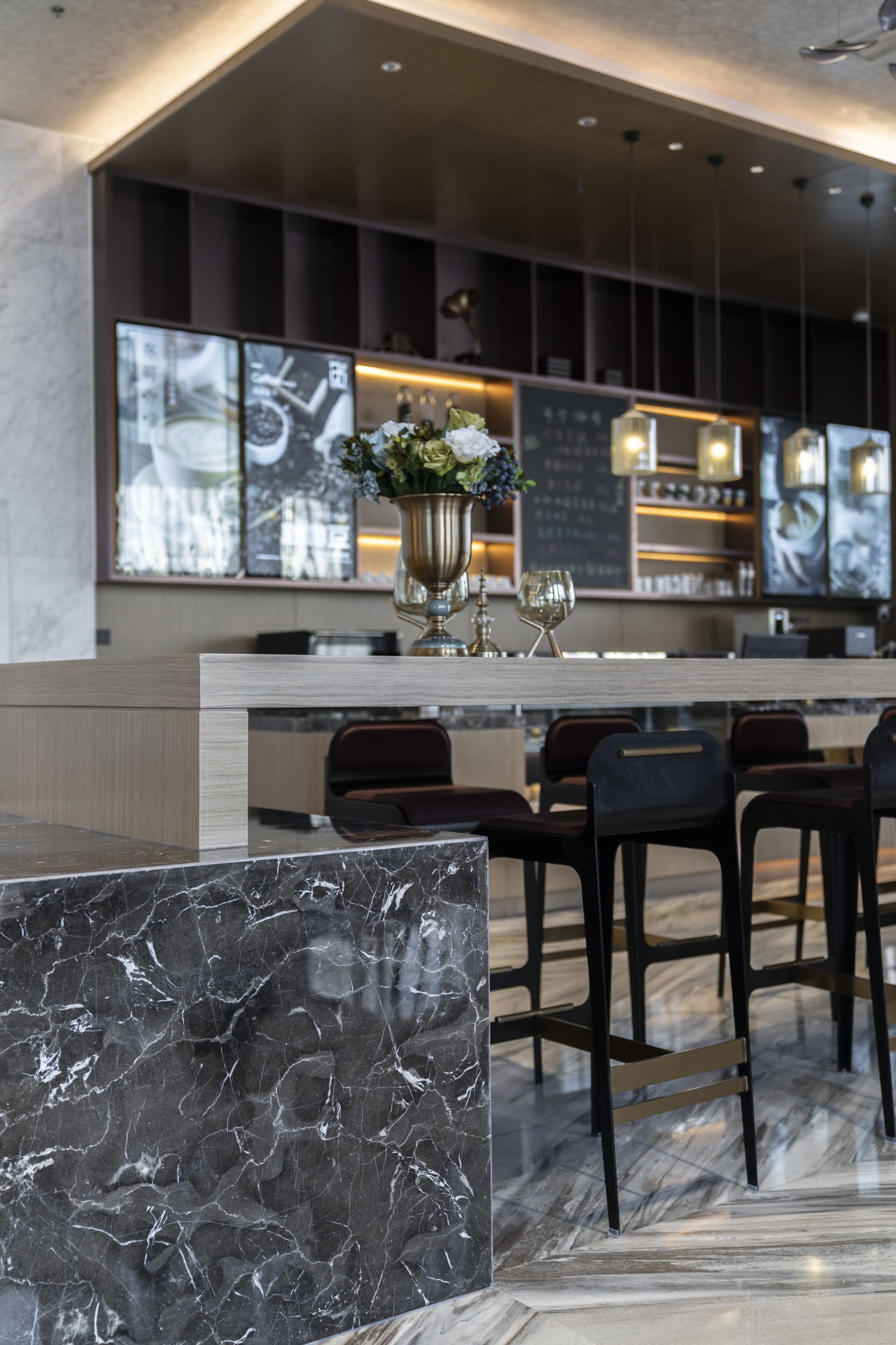 A modern bar area with marble countertops, bar stools, and a central decorative vase.