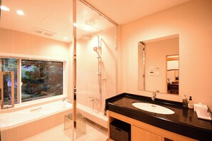 A modern bathroom with a glass shower enclosure, a bathtub, and a large window offering a view of greenery.