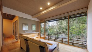 A modern interior with a sofa, a small table, and a large window offering a view of trees.