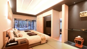 A modern bedroom with a large bed, bedside tables, a TV, and a view of the outdoors.