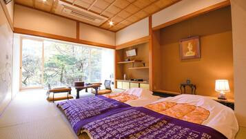 A traditional Japanese-style room with tatami flooring, a bed with a purple and orange bedding, a desk, and a chair.