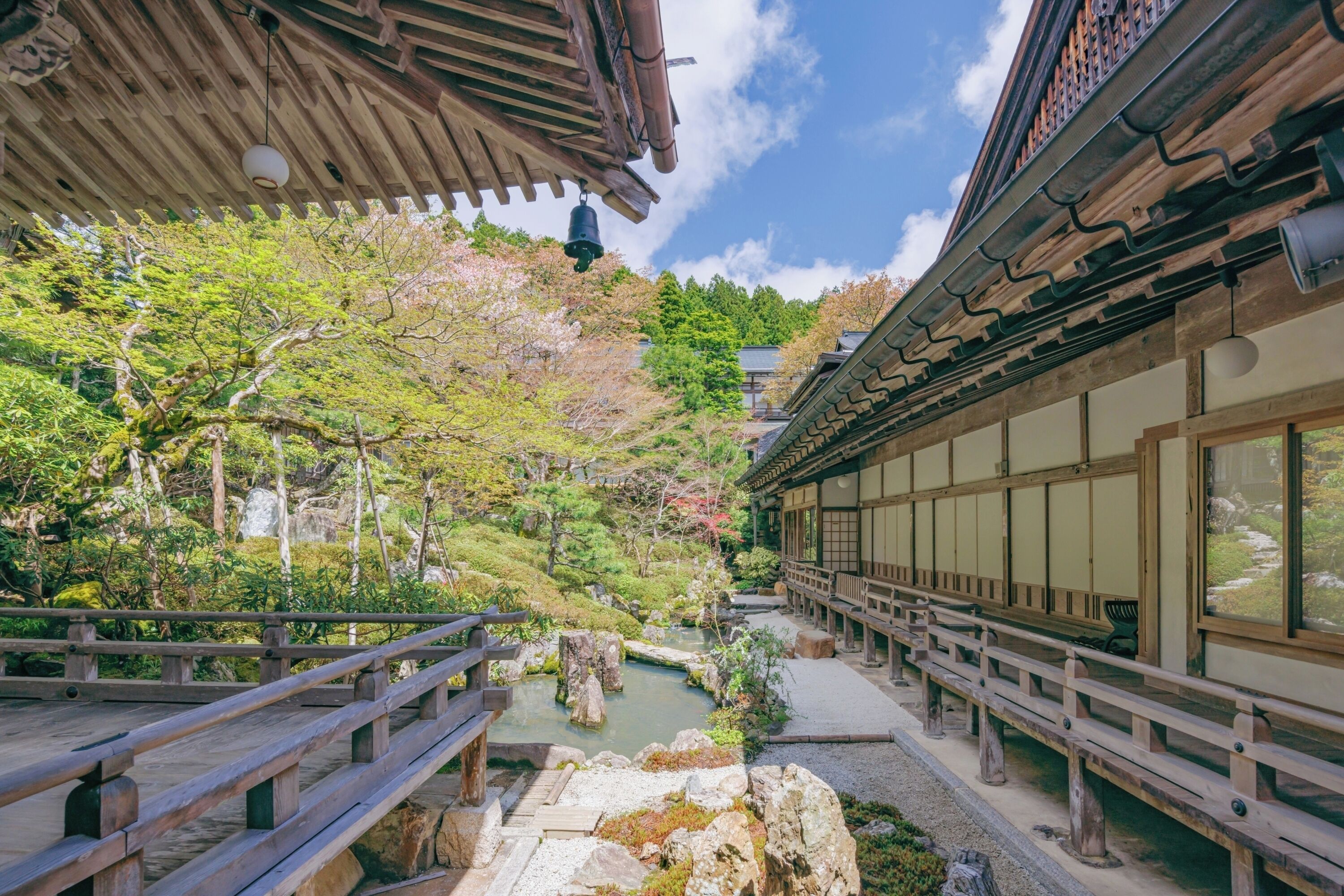 Un jardín japonés tradicional con un puente de madera, faroles de piedra y un estanque de carpas.